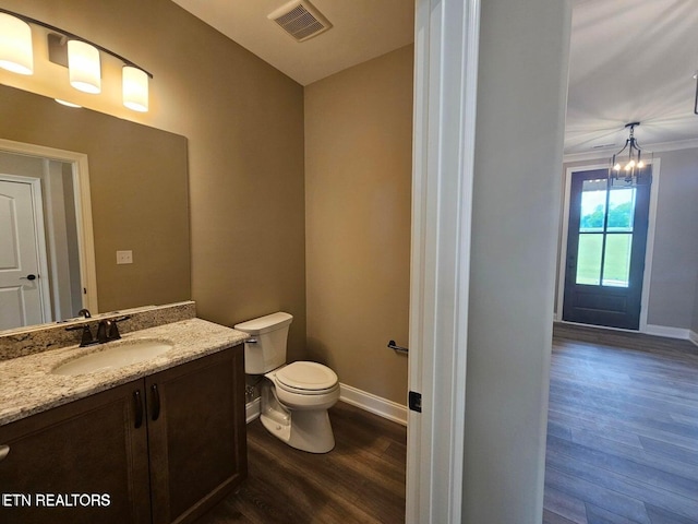 bathroom with hardwood / wood-style floors, vanity, toilet, and a notable chandelier