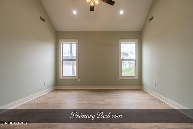 unfurnished room with hardwood / wood-style flooring, vaulted ceiling, a wealth of natural light, and ceiling fan