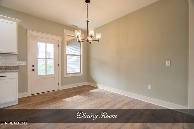 unfurnished dining area featuring light hardwood / wood-style flooring and a chandelier