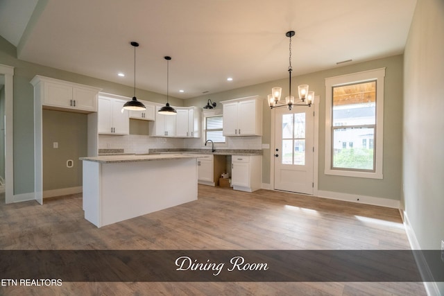 kitchen featuring pendant lighting, a center island, white cabinetry, and light hardwood / wood-style flooring