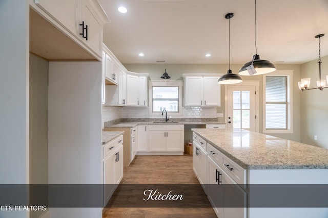 kitchen with decorative backsplash, hardwood / wood-style floors, a center island, and white cabinetry