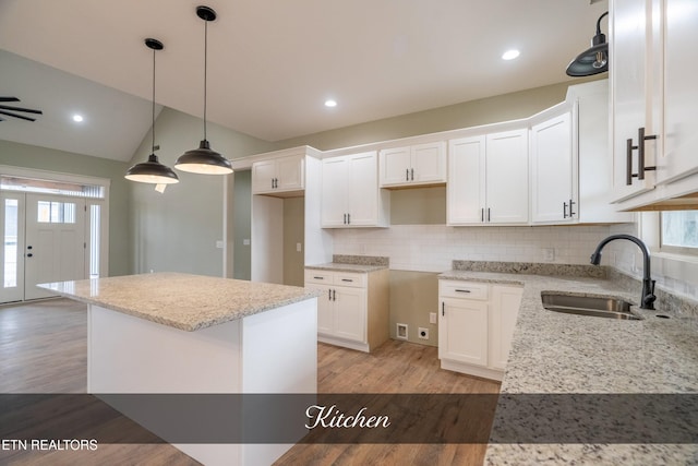 kitchen with white cabinets, a wealth of natural light, sink, and a kitchen island