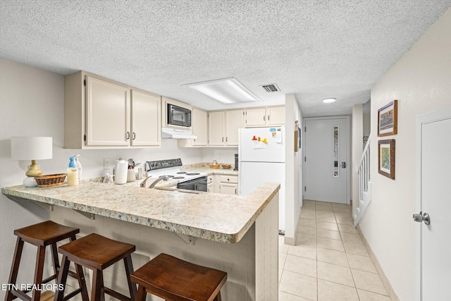 kitchen with a breakfast bar area, kitchen peninsula, light tile patterned flooring, and white appliances