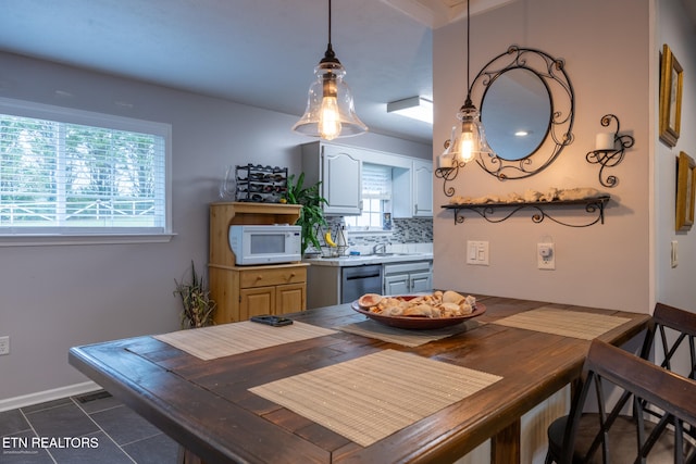 dining space with dark tile patterned flooring, plenty of natural light, and sink