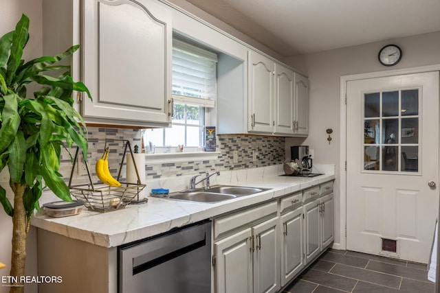 kitchen with decorative backsplash, white cabinetry, stainless steel dishwasher, and sink