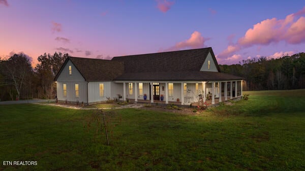 back of property at dusk featuring a lawn