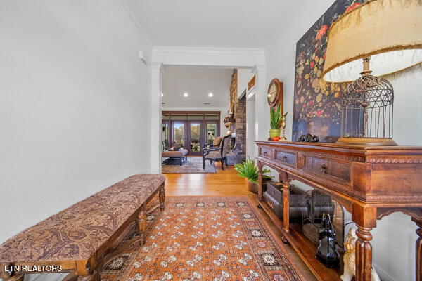 hallway featuring wood-type flooring, decorative columns, french doors, and crown molding