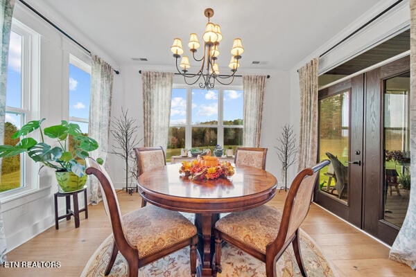 dining room featuring crown molding, french doors, light hardwood / wood-style flooring, and an inviting chandelier