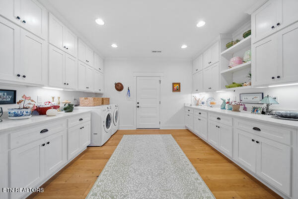 laundry room with light hardwood / wood-style floors, cabinets, and washing machine and clothes dryer