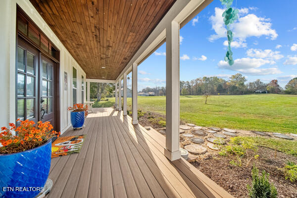 wooden terrace with covered porch and a yard