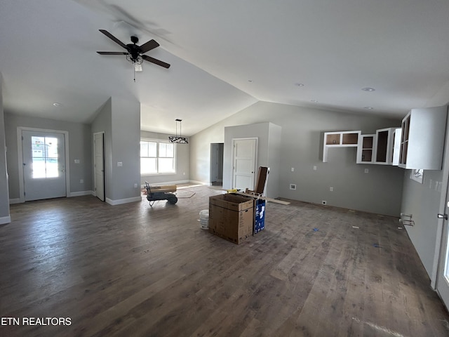 unfurnished living room with ceiling fan with notable chandelier, dark wood-type flooring, and vaulted ceiling