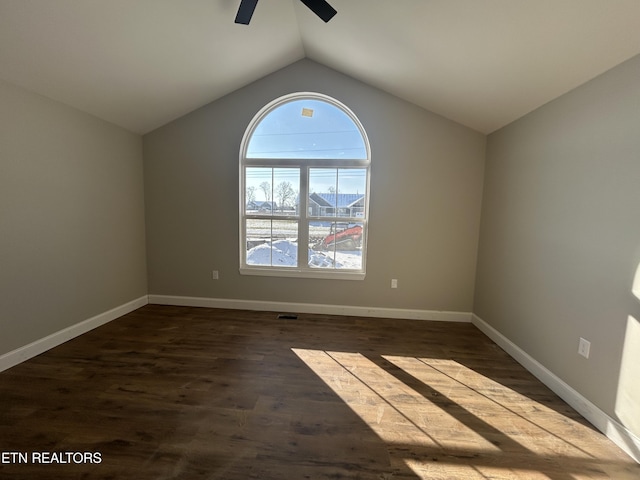 empty room with ceiling fan, dark hardwood / wood-style floors, and vaulted ceiling