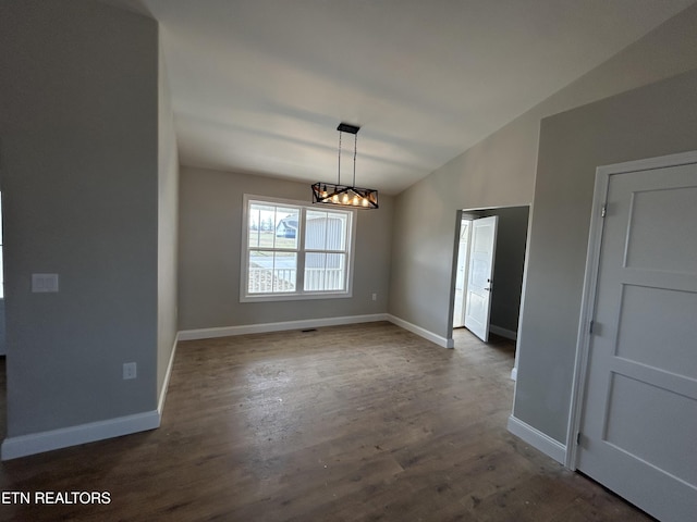 unfurnished dining area with dark wood finished floors, a notable chandelier, vaulted ceiling, and baseboards