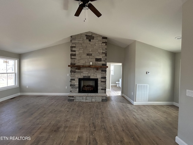 unfurnished living room with visible vents, a stone fireplace, baseboards, and wood finished floors