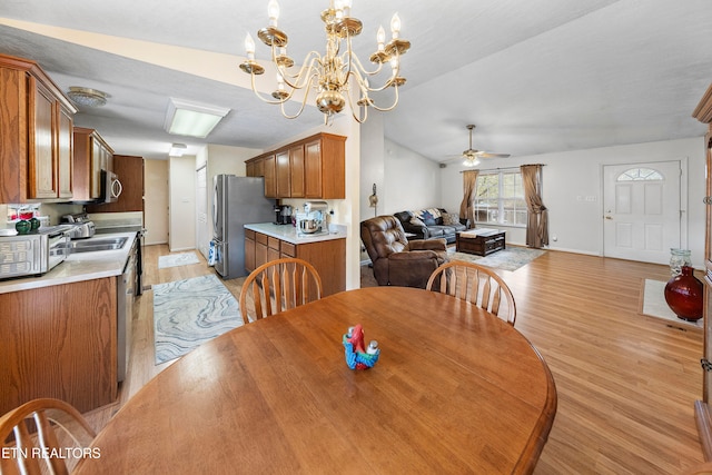 dining space featuring lofted ceiling, light hardwood / wood-style flooring, and ceiling fan with notable chandelier