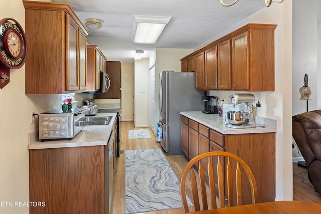 kitchen featuring stainless steel appliances, a textured ceiling, and light wood-type flooring