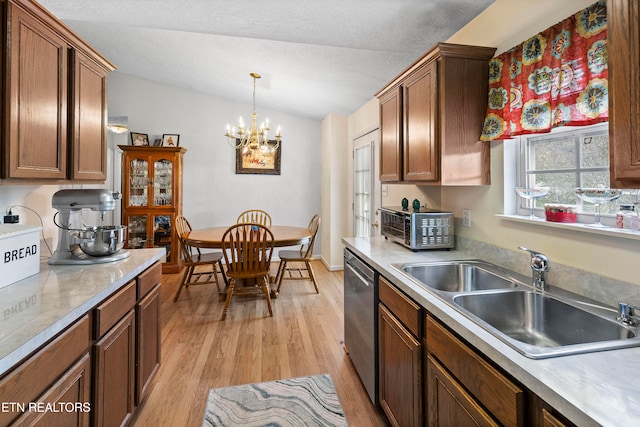 kitchen with pendant lighting, dishwasher, sink, light hardwood / wood-style flooring, and a notable chandelier