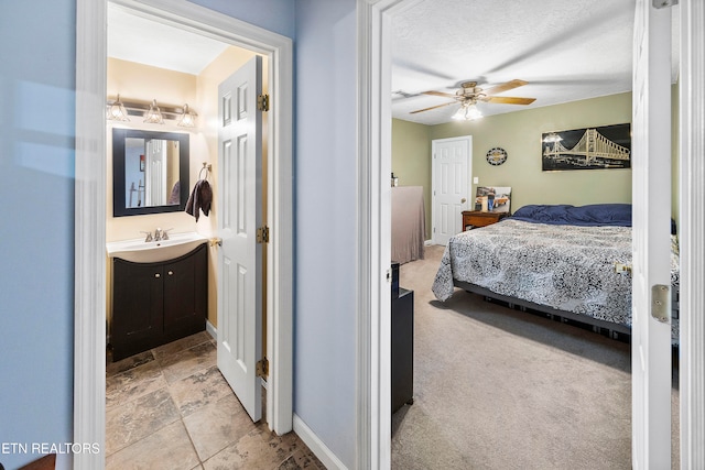 carpeted bedroom featuring connected bathroom, ceiling fan, sink, and a textured ceiling