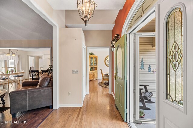 hallway with a notable chandelier, a healthy amount of sunlight, and light hardwood / wood-style floors