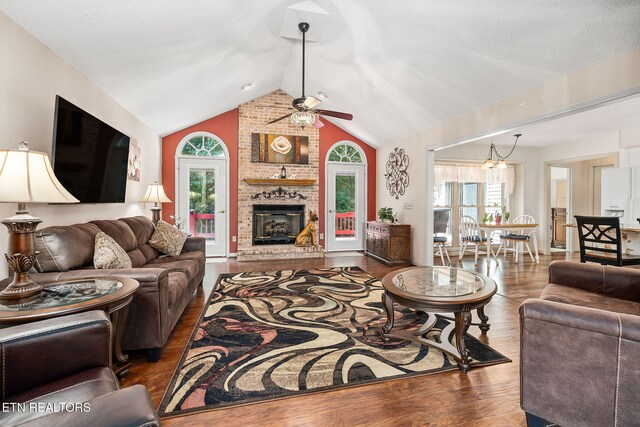 living room featuring ceiling fan, dark hardwood / wood-style floors, lofted ceiling, and a brick fireplace