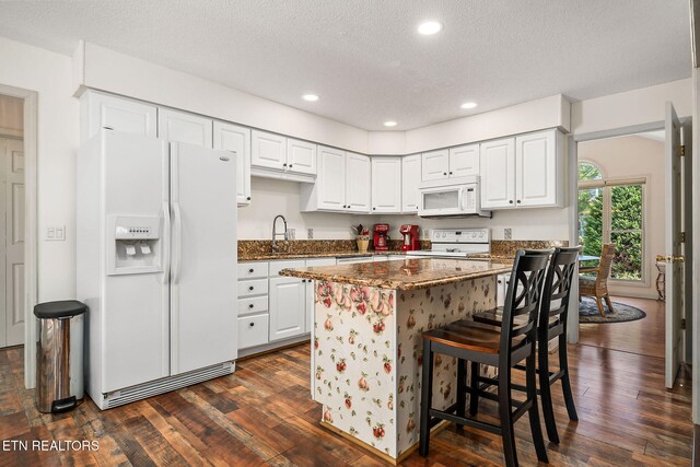 kitchen featuring white cabinetry, dark hardwood / wood-style floors, and white appliances