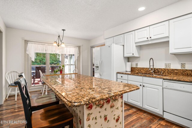 kitchen with a textured ceiling, white appliances, dark wood-type flooring, dark stone countertops, and white cabinetry