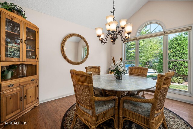 dining space featuring dark hardwood / wood-style flooring, an inviting chandelier, and lofted ceiling