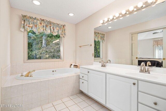 bathroom with tiled bath, tile patterned flooring, vanity, and a healthy amount of sunlight