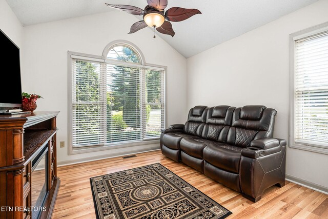 living room featuring ceiling fan, light wood-type flooring, and vaulted ceiling