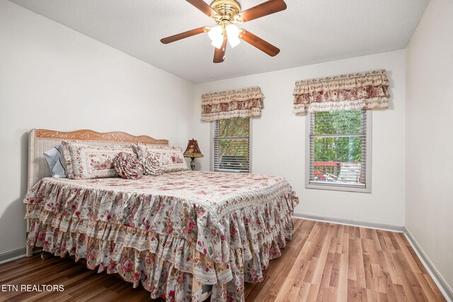 bedroom with ceiling fan, wood-type flooring, and a textured ceiling