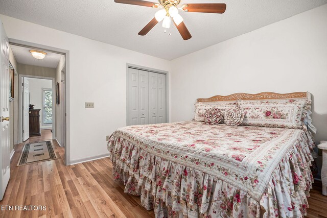 bedroom featuring a textured ceiling, light wood-type flooring, a closet, and ceiling fan