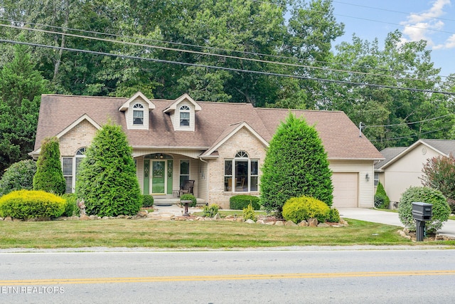 view of front of home with covered porch, a garage, and a front yard