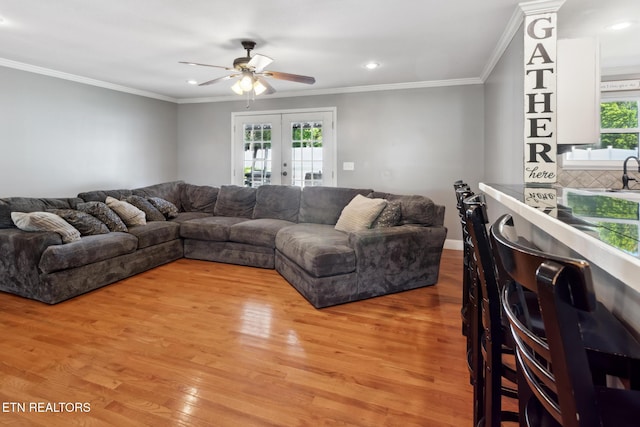 living room with plenty of natural light, french doors, ornamental molding, and light hardwood / wood-style flooring