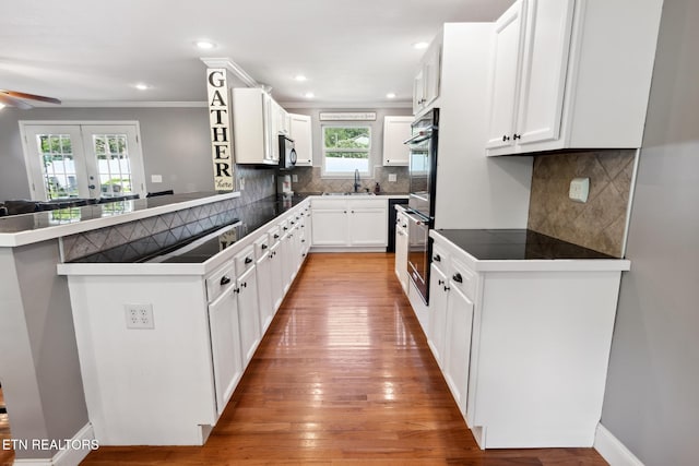 kitchen featuring kitchen peninsula, plenty of natural light, white cabinets, and light hardwood / wood-style flooring