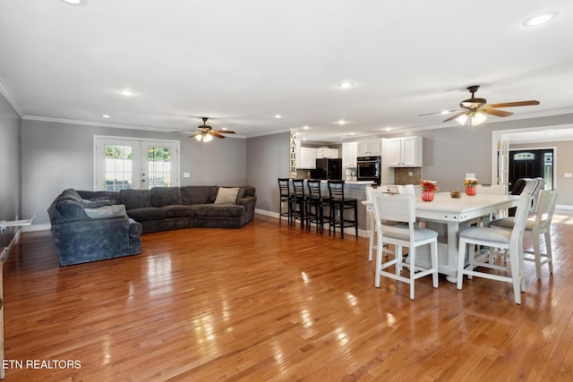 living room featuring ceiling fan, ornamental molding, french doors, and light hardwood / wood-style flooring