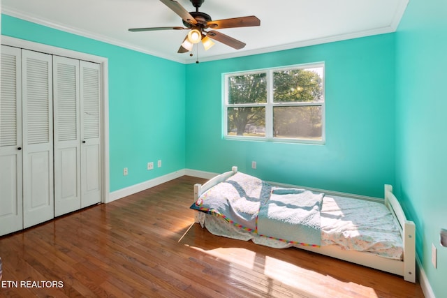 bedroom featuring ceiling fan, wood-type flooring, crown molding, and a closet