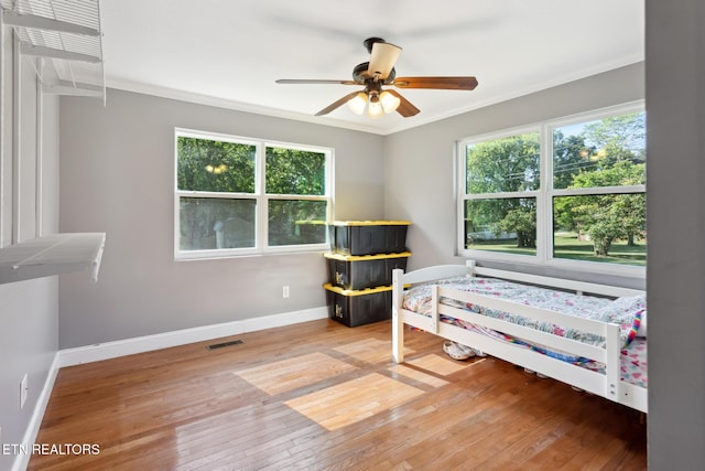 bedroom featuring ceiling fan, wood-type flooring, and ornamental molding