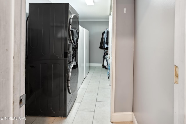 washroom with light tile patterned flooring, stacked washing maching and dryer, and ornamental molding