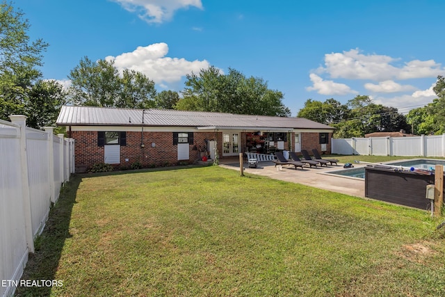 back of house featuring french doors, a yard, a fenced in pool, and a patio area