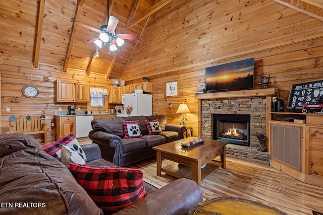 living room with beamed ceiling, light wood-type flooring, a fireplace, and wood ceiling