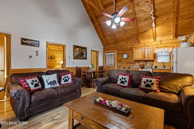 living room with beamed ceiling, light hardwood / wood-style flooring, high vaulted ceiling, and wooden walls