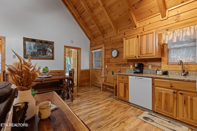 kitchen with dishwasher, sink, beamed ceiling, wood walls, and light wood-type flooring