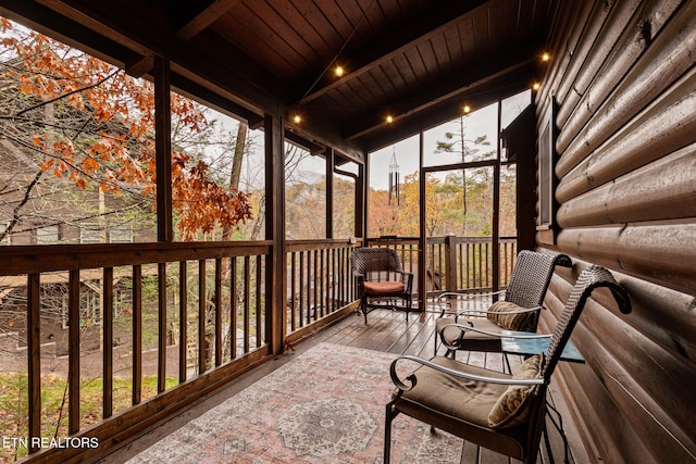 unfurnished sunroom with vaulted ceiling with beams, a wealth of natural light, and wooden ceiling