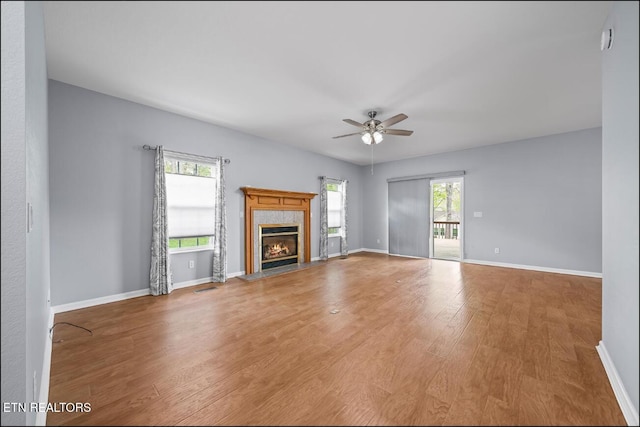 unfurnished living room with hardwood / wood-style flooring, a premium fireplace, and a wealth of natural light