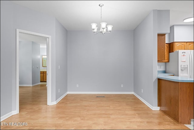 unfurnished dining area with light hardwood / wood-style flooring and a notable chandelier