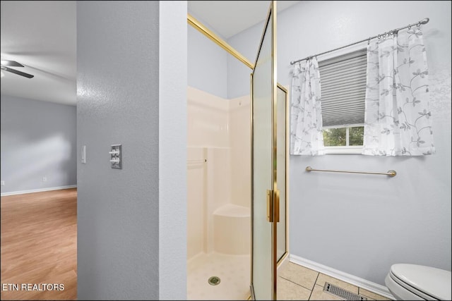 bathroom with hardwood / wood-style floors, ceiling fan, toilet, and walk in shower