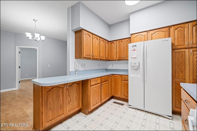 kitchen featuring kitchen peninsula, pendant lighting, white fridge with ice dispenser, and a chandelier