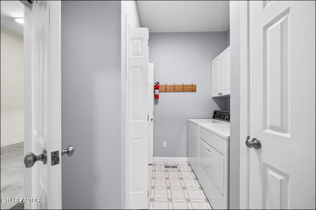 laundry area with separate washer and dryer and cabinets