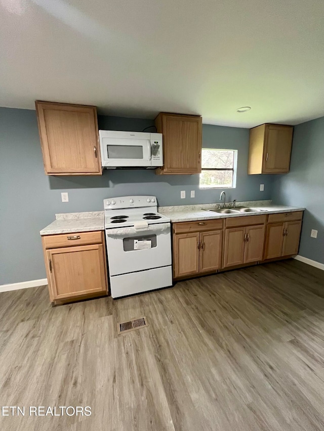 kitchen featuring sink, light hardwood / wood-style floors, and white appliances