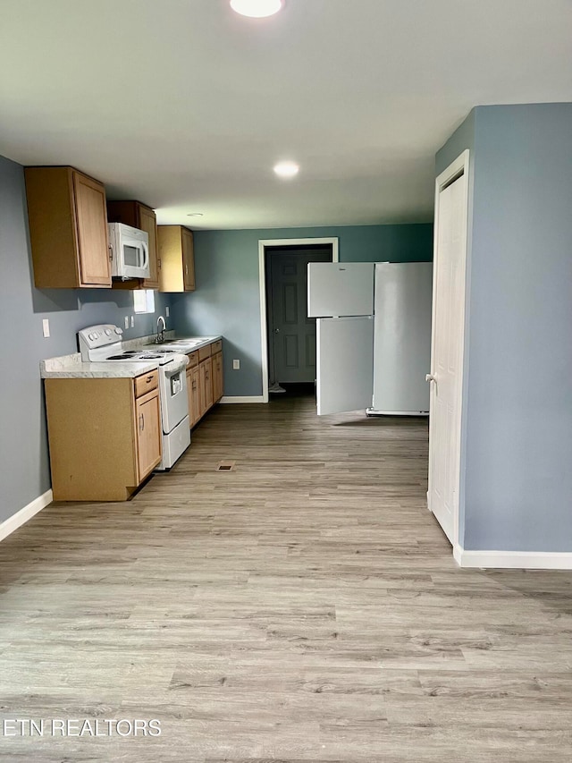 kitchen featuring light wood-type flooring, white appliances, and sink